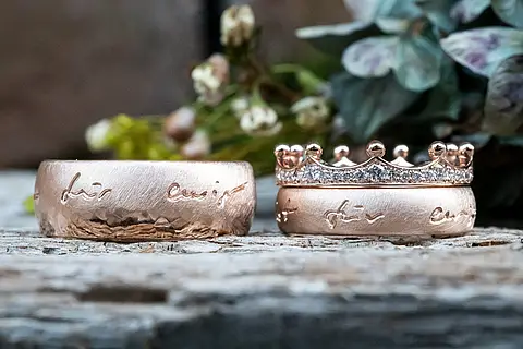 Besondere Trauringe aus Roségold und Rotgold mit handlettering und einem Vorsteckring in Kronenform aus Rotgold mit Brillanten