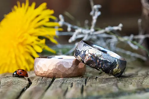 Ausgefallene Trauringe aus Rotgold und Weißgold, der Rotgoldene Ring hat eine strukturierte Hammerschlag Oberfläche, der Weißgoldring hat eine rustikale schwarze Oberfläche