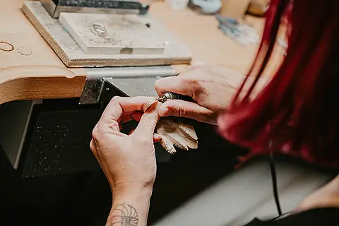 Goldschmiedemeisterin Birte Schumacher bearbeitet einen Partnerring am Werktisch.