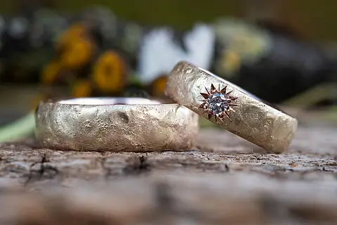 Individuelle Eheringe aus Weißgold mit einer liquid Oberfläche und einem großen Brillanten als Stern eingefasst.