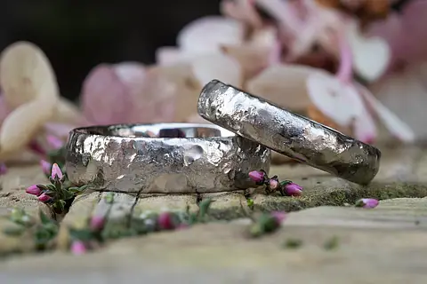 Silberne Eheringe aus Weißgold mit einer Oberfläche die wie flüssiges Metall aussieht