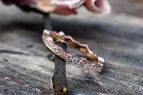 Verlobungsring aus Roségold, eine Seite ist gerade und schmiegt sich an den Trauring an, die andere sieht aus wie ein feines Krönchen mit Brillanten. Der Verlobungsring ist als Vorsteckring gedacht