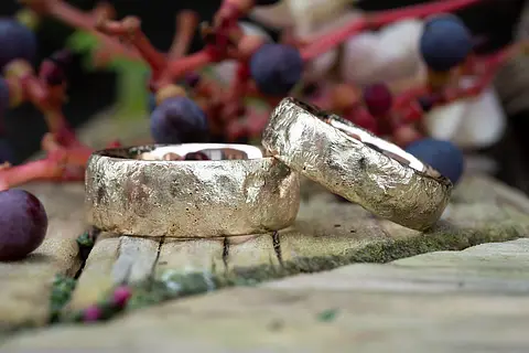 Ausgefallene Trauringe aus Rotgold mit einer rustikalen Struktur, die wie flüssiges Metall aussieht