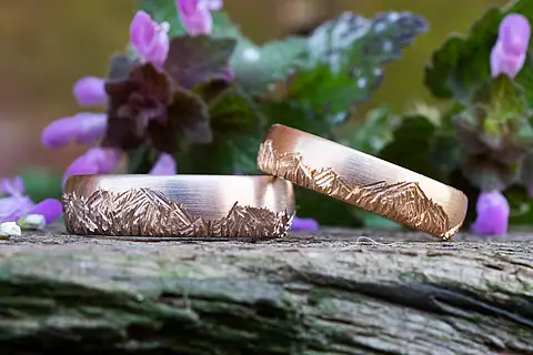 Individuelle Eheringe aus Roségold und Rosé-Palladium mit einer rustikalen Oberfläche in die Silhouetten von Bergen eingearbeitet sind