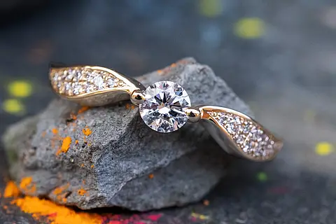 Verlobungsring Rosalie aus Roségold mit einem Diamanten als Mittelstein und besetzter Ringschiene die aussieht wie Flügel