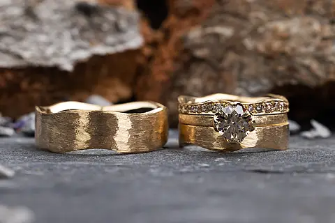 Strukturiertes Eheringset, der rechte Ring hat zwei Vorsteckringe, einen mit kleinen Diamanten entlang der Ringschiene, einen mit großem Solitär.