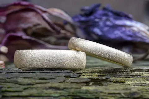 Goldene Eheringe mit einer seidenmatten Ringoberfläche.