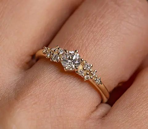 Verlobungsring aus Roségold mit Diamanten an einer Frauenhand.