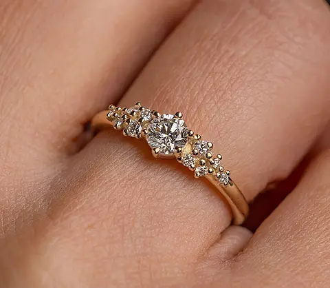 Verlobungsring aus Roségold mit Diamanten an einer Frauenhand.