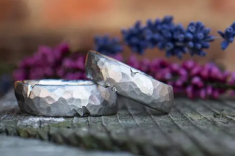 Besondere Trauringe aus Weißgold oder Platin mit einer Hammerschlag Oberfläche, je drei kleinen Kerben und winzigen Steinen (Brillanten) im Damenring