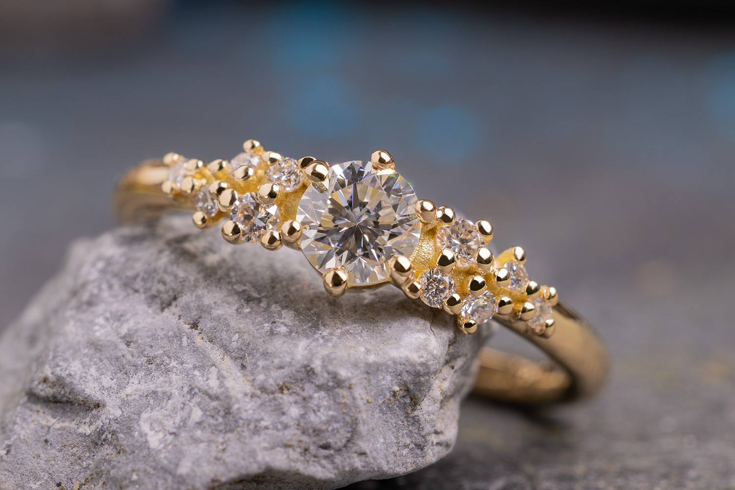 Verlobungsring Little Mermaid aus Gelbgold mit unterschiedlich großen Diamanten um einen Mittelstein herum